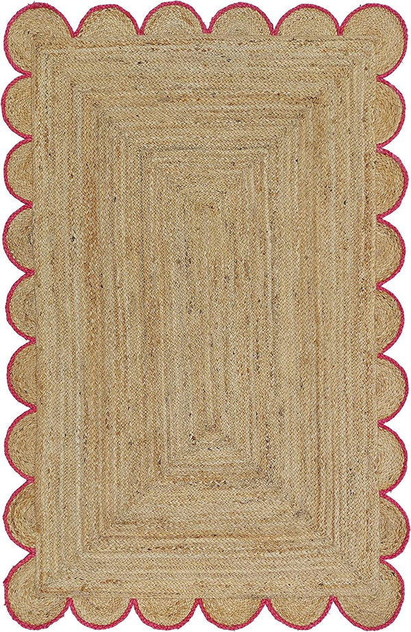 Handwoven natural jute area rug with pink scalloped border in a modern Scandinavian living room.