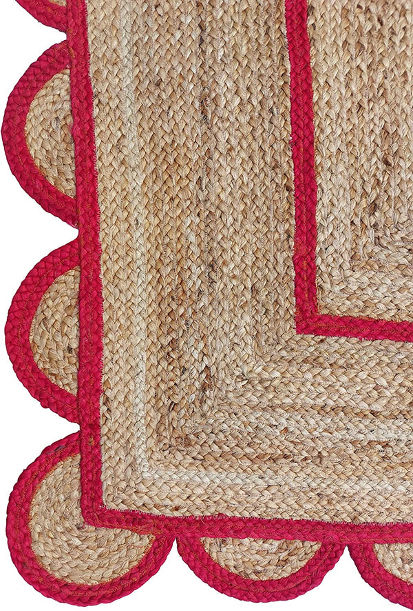 Handwoven natural jute area rug with bold red scalloped border and braided rectangular design