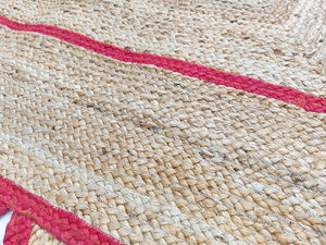 Handwoven natural jute area rug with bold red scalloped border and braided rectangular design
