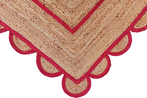 Handwoven natural jute area rug with bold red scalloped border and braided rectangular design