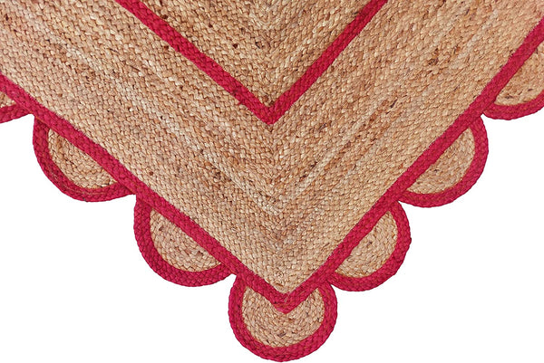 Handwoven natural jute area rug with bold red scalloped border and braided rectangular design