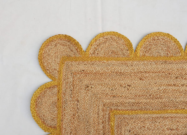 Handmade natural jute scalloped area rug with mustard border in a modern boho living room