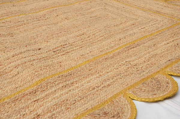 Handmade natural jute scalloped area rug with mustard border in a modern boho living room