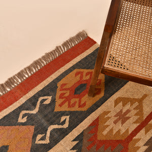 Handmade wool jute kilim area rug featuring Southwestern tribal geometric patterns in beige, charcoal, rust, and ivory for boho farmhouse home décor.
