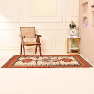 Handwoven ivory wool Kilim area rug featuring tribal geometric medallions and traditional border design, styled in a modern living room.