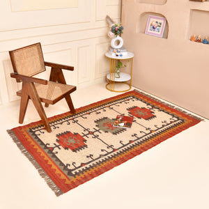 Handwoven ivory wool Kilim area rug featuring tribal geometric medallions and traditional border design, styled in a modern living room.
