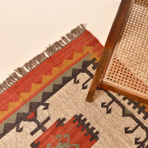 Handwoven ivory wool Kilim area rug featuring tribal geometric medallions and traditional border design, styled in a modern living room.