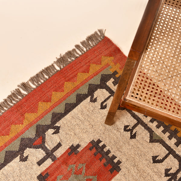 Handwoven ivory wool Kilim area rug featuring tribal geometric medallions and traditional border design, styled in a modern living room.