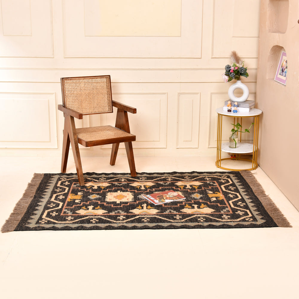 Handwoven black wool jute Kilim area rug with tribal geometric pattern and fringe in a modern living room.