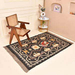 Handwoven black wool jute Kilim area rug with tribal geometric pattern and fringe in a modern living room.
