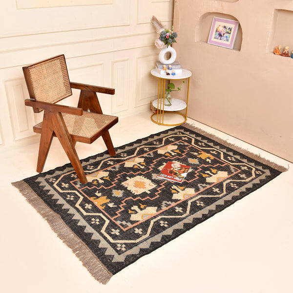 Handwoven black wool jute Kilim area rug with tribal geometric pattern and fringe in a modern living room.