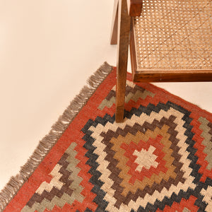 Handwoven geometric wool jute kilim area rug with tribal diamond pattern in terracotta, beige, charcoal, and ivory colors for living room and bedroom décor.