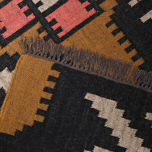 Handwoven ivory wool jute Kilim area rug featuring bold tribal geometric patterns with black, camel, and blush accents in a modern living room.