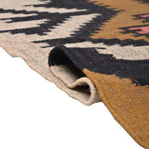Handwoven ivory wool jute Kilim area rug featuring bold tribal geometric patterns with black, camel, and blush accents in a modern living room.