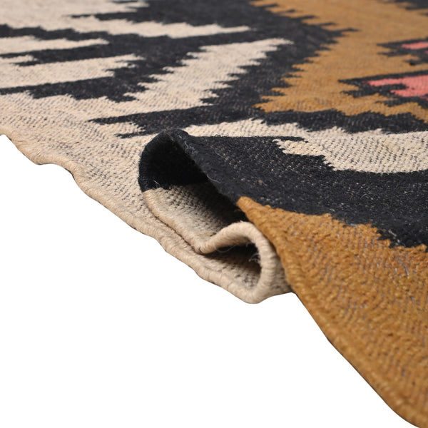 Handwoven ivory wool jute Kilim area rug featuring bold tribal geometric patterns with black, camel, and blush accents in a modern living room.