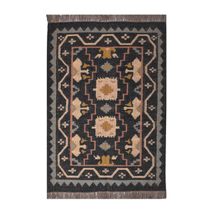 Handwoven black wool jute Kilim area rug with tribal geometric pattern and fringe in a modern living room.