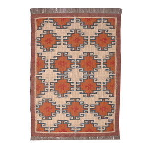 Handwoven wool jute kilim area rug with geometric tribal pattern in terracotta, ivory, and blue tones placed in a modern living room.