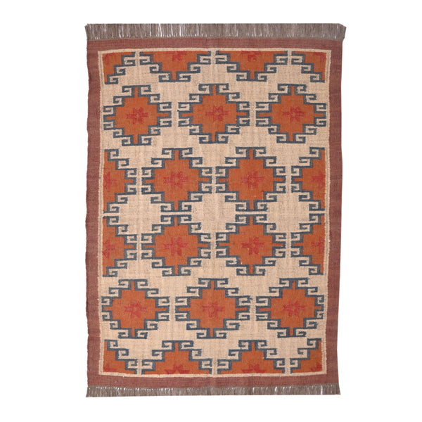 Handwoven wool jute kilim area rug with geometric tribal pattern in terracotta, ivory, and blue tones placed in a modern living room.