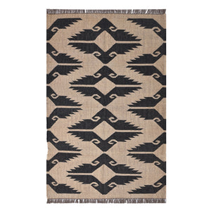 Handwoven black and ivory geometric kilim wool jute area rug in a modern living room with wooden chair and side table.