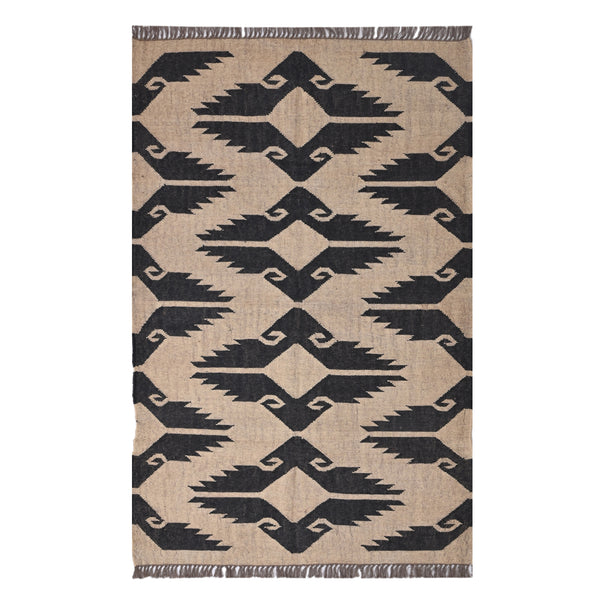 Handwoven black and ivory geometric kilim wool jute area rug in a modern living room with wooden chair and side table.
