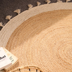 Handwoven round natural jute rug with ivory white braided border and tassel fringe for boho farmhouse home décor.