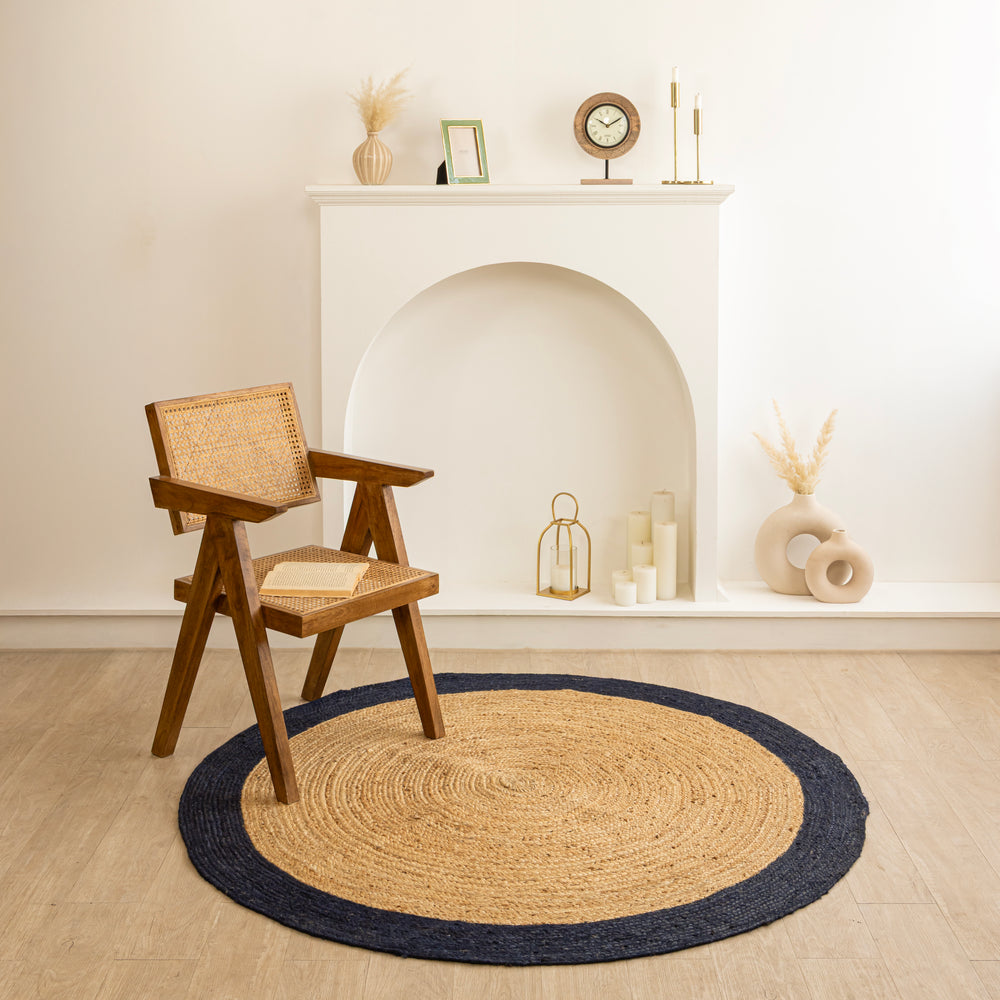 Natural beige circular jute rug with a dark navy border in a minimalist modern living room.