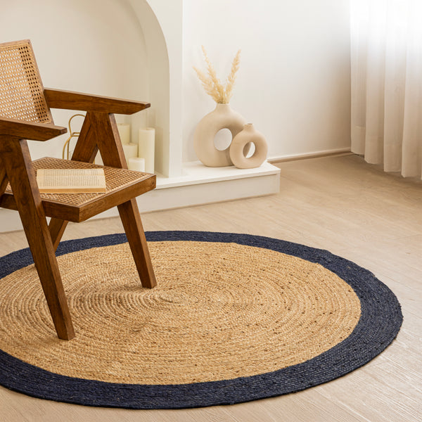 Natural beige circular jute rug with a dark navy border in a minimalist modern living room.