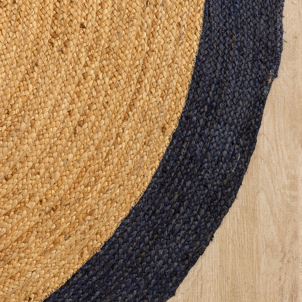 Natural beige circular jute rug with a dark navy border in a minimalist modern living room.
