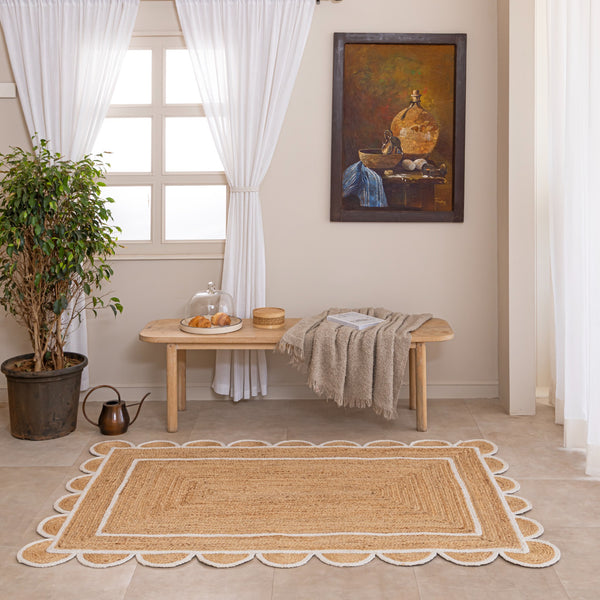 Handmade natural jute area rug with scalloped braided border in a neutral beige living room