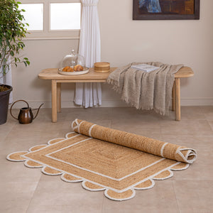 Handmade natural jute area rug with scalloped braided border in a neutral beige living room