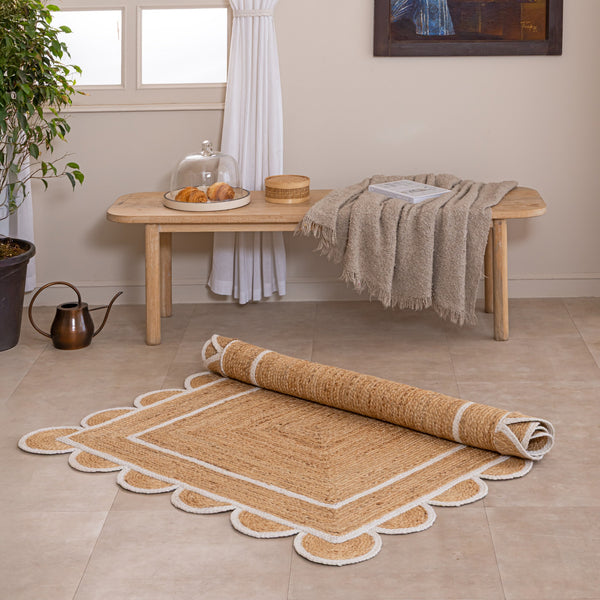 Handmade natural jute area rug with scalloped braided border in a neutral beige living room