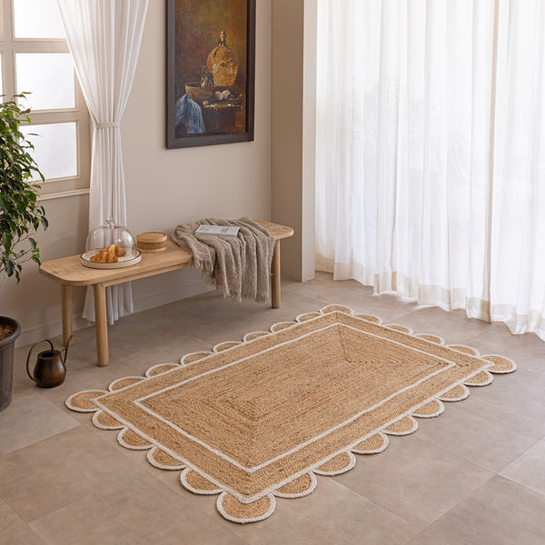 Handmade natural jute area rug with scalloped braided border in a neutral beige living room