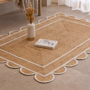 Handmade natural jute area rug with scalloped braided border in a neutral beige living room