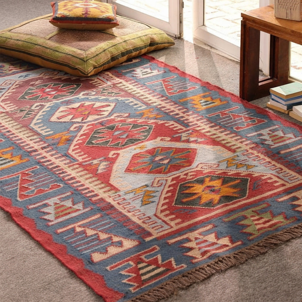 Handmade blue and red bohemian geometric tribal area rug displayed in a stylish living room.