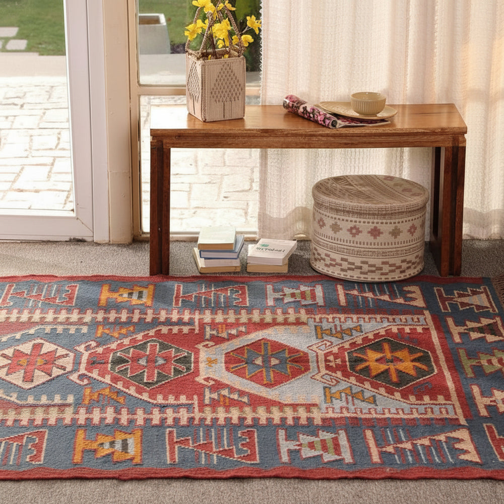 Handmade blue and red bohemian geometric tribal area rug displayed in a stylish living room.