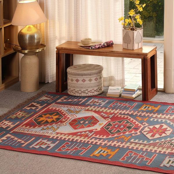 Handmade blue and red bohemian geometric tribal area rug displayed in a stylish living room.