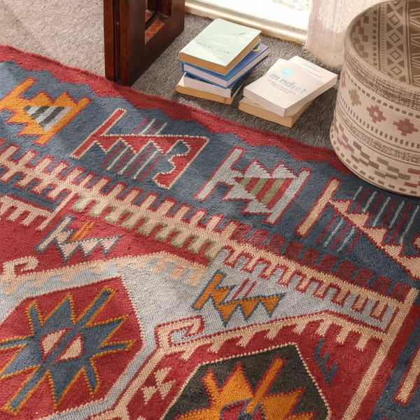 Handmade blue and red bohemian geometric tribal area rug displayed in a stylish living room.
