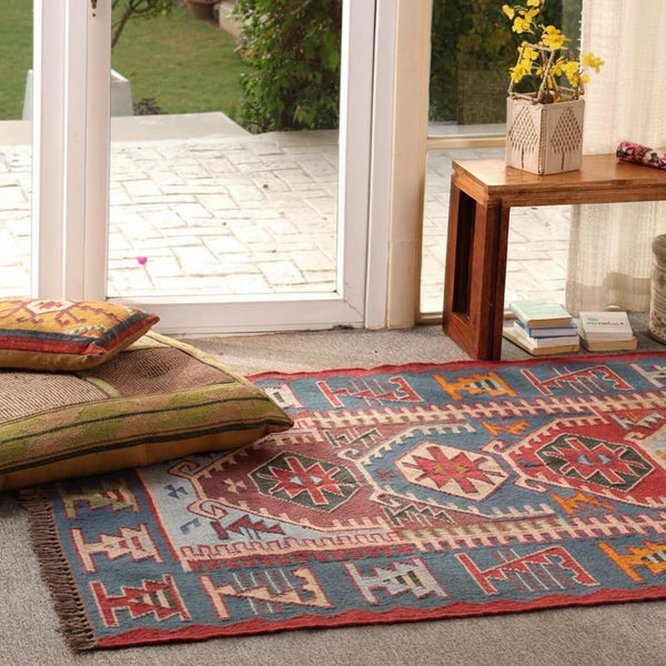 Handmade blue and red bohemian geometric tribal area rug displayed in a stylish living room.